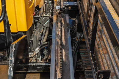 2018 Vermeer D24x40 S3 thrust frame rack-and-pinion gear rail, hydraulic hoses, and track undercarriage close-up