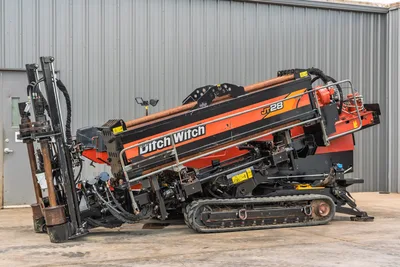 2021 Ditch Witch JT28 HDD drill, driver-side view, drill frame angled up, drill pipe loaded, rubber tracks, hydraulic components visible