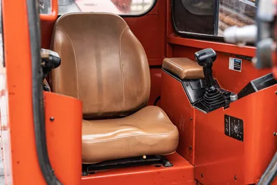 2016 Ditch Witch JT25 operator cab interior showing tan vinyl seat, joystick controls, and orange steel enclosure