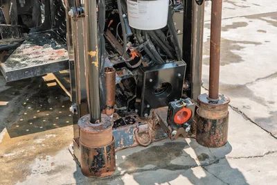 2023 Ditch Witch JT20 drill frame base, worn anchor posts, hydraulic hoses, vise block, and stabilizer feet with heavy field wear