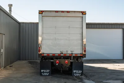 Rear view of 2000 Freightliner FL80 mud truck featuring a box body, rear spotlights, and mud flaps.