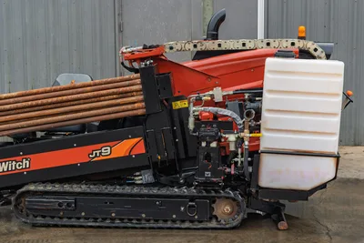 2016 Ditch Witch JT9 HDD drill, side view, rubber tracks, loaded drill pipe rack, exposed hydraulics, fluid tank visible