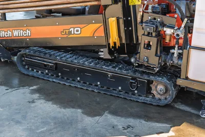 Ditch Witch JT10 tracked HDD machine side view showing rubber tracks, engine compartment, hydraulic manifold, and drill head assembly