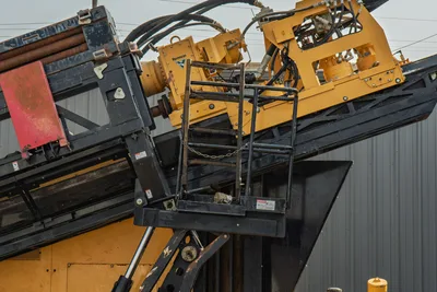2017 Vermeer D100x140 S3 drill frame close-up showing carriage, hydraulic lines, vise assembly, and access ladder with safety chain