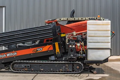 2018 Ditch Witch JT10 HDD drill, side view showing drill pipe rack, hydraulic components, fluid tank, and rubber tracks