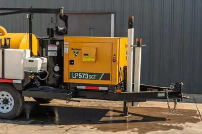 Side profile of 2024 Vermeer LP573SGT vacuum excavator showing yellow engine compartment, trailer hitch, and wand holders.