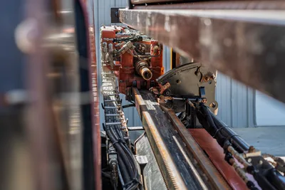 Close-up of Ditch Witch JT20 carriage, drill rack, hydraulic hoses, and rotation drive assembly on the drill stem track.