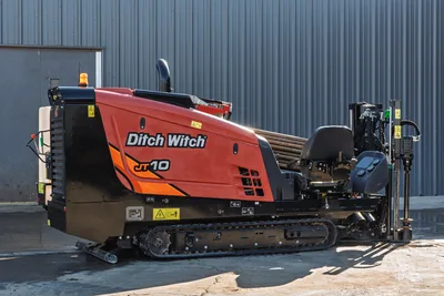 Ditch Witch JT10 HDD unit, side view, red/orange cab, tracked undercarriage, drill pipe visible, 9000 lb thrust