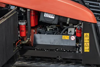 2021 Ditch Witch JT40 engine compartment open, showing Baldwin filters, hydraulic lines, Cummins ECM, and safety decals