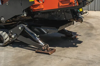 Low-angle view of 2021 Ditch Witch JT20 drill rig, focusing on hydraulic stabilizer legs, frame, and rubber track assembly.