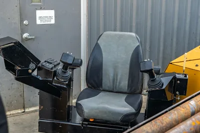 2016 Vermeer D23x30 S3 operator seat with dual joystick controls, worn gray-black cushioning, drill pipe visible at right
