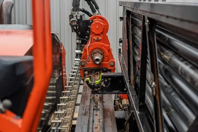 2021 Ditch Witch JT40 spindle and rotary head close-up, rack-and-pinion carriage, hydraulic lines, stacked drill pipe visible right