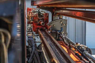 2021 Ditch Witch JT20 carriage, rack and pinion drill rack, hydraulic lines, and rotation gearbox in close-up side profile.