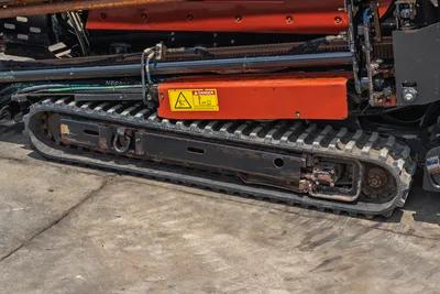 2017 Ditch Witch JT20 rubber track close-up showing drive sprocket, danger warning label, hydraulic lines, and drill frame