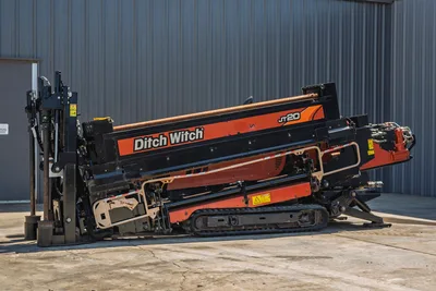2018 Ditch Witch JT20 horizontal directional drill side view featuring rubber tracks, drill pipe, and engine compartment.