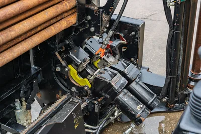 2016 Ditch Witch JT9 spindle/rotary head closeup showing pipe rack, hydraulic lines, vise jaws, and rack-and-pinion drive