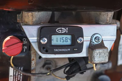 2016 Belshe WB14-2EP trailer: close-up of tach/hour meter (1158.4 hrs) and red on/off switch; field view.