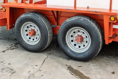 2019 Belshe WB14-2EP mud mixing trailer tandem axle close-up showing dual trailer tires, gray steel wheels, orange frame