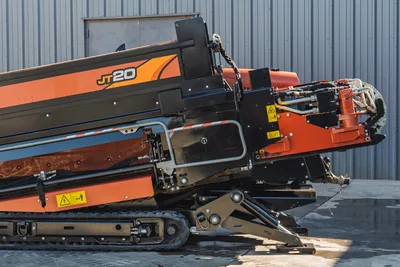 Side profile of Ditch Witch JT20 HDD drill showing carriage, hydraulic connections, stabilizers, and undercarriage tracks.