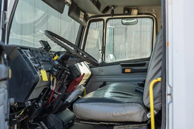 Interior cab view of 2000 Freightliner FL80 mud truck featuring steering column, dashboard gauges, and vinyl bench seat.