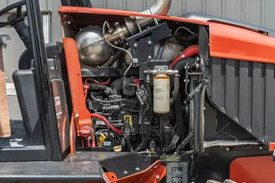 2024 Ditch Witch RT125Q open engine compartment showing diesel engine, fuel filter, exhaust, red wiring harness, and radiator screen