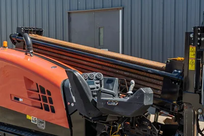 2018 Ditch Witch JT20 operator station, side-angle view showing drill pipe rack, control console, and engine compartment.