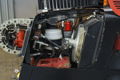 2015 Ditch Witch JT20 open engine compartment showing hydraulic hoses, coolant reservoir, oil filter, and cooling fan