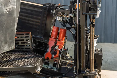 Close-up of Ditch Witch JT24 drill pipe, hydraulic cylinders, and engine cooling system from a side-angle perspective.