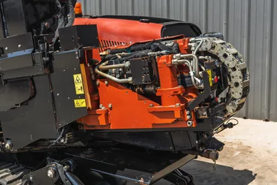 2021 Ditch Witch JT20 drill carriage close-up showing hydraulic lines, drive chain, spindle, and safety labels on orange frame