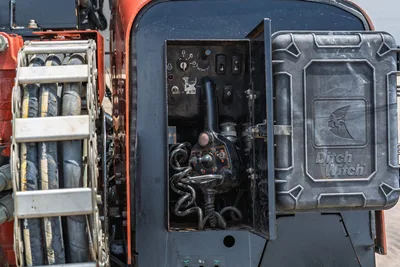 2017 Ditch Witch JT20 open control panel showing joystick, toggle switches, hydraulic hoses, and drill pipe rack visible at left