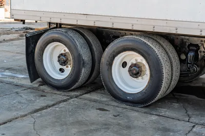 2000 Freightliner FL80 mud truck rear tandem wheels and tires, side profile view showing tread condition and steel rims.