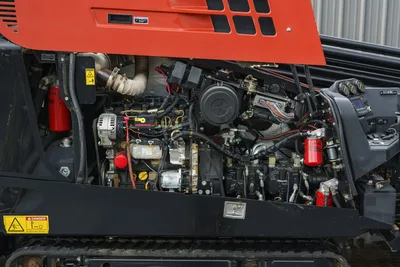 2015 Ditch Witch JT20 open engine compartment showing 74hp engine, alternator, hydraulic filters, wiring harness, and operator controls panel
