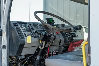 Interior cab view of 2000 Freightliner FL80 mud truck showcasing steering wheel, instrument cluster, and dash controls.