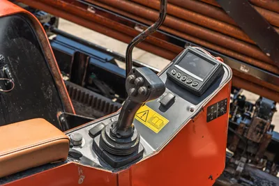 2021 Ditch Witch JT28 operator console, joystick controls, digital display, warning labels, tan seat; used drill pipe visible overhead