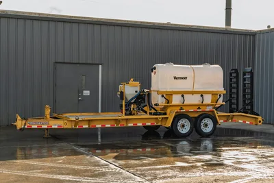 2021 TowMaster T-20D yellow tandem-axle trailer with Vermeer MX125 mud mixer, white poly tank, hopper, and pipe rack, side view