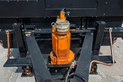 2023 American Augers M300DH submersible mud pump, orange, wear-worn, mounted between trailer frame rails with hydraulic hose connections