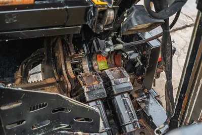 Close-up of Ditch Witch JT20 drill pipe vise assembly, showing hydraulic clamps and steel housing, operational condition.