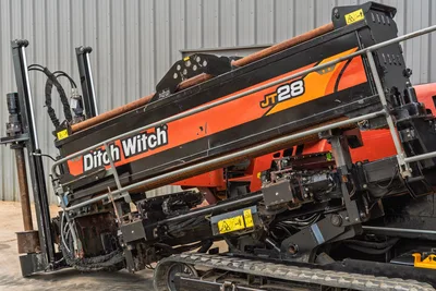 2021 Ditch Witch JT28 HDD drill, close-up of elevated drill frame with loaded pipe, hydraulics, rubber tracks visible