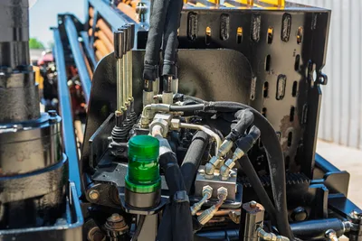 Close-up of Ditch Witch JT30 All Terrain hydraulic control manifold, levers, and protective hose wrapping on drilling rig.