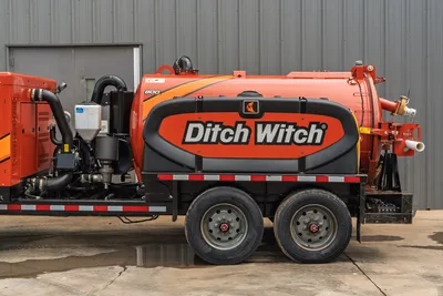 2023 Ditch Witch HX50 vacuum excavator, side view, 800-gal orange debris tank, dual-axle trailer, visible pump, hose fittings, and discharge port