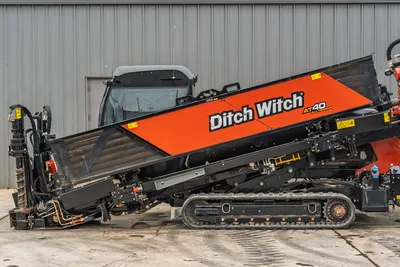 Side profile of 2021 Ditch Witch AT40 All Terrain HDD drill featuring cab, steel tracks, and rack of drill pipe.