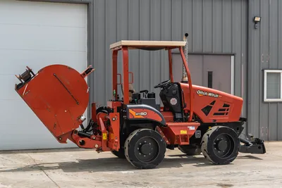 Side view, 2017 Ditch Witch RT80 trencher, wheeled utility tractor with rear attachment, canopy, and engine compartment.