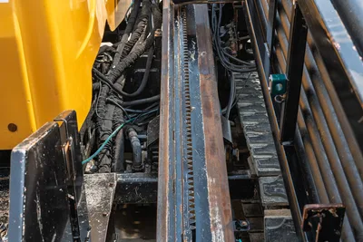 Vermeer 24x40 Series II drill rack and pinion gear drive system with exposed hydraulic hoses and metal tracks.