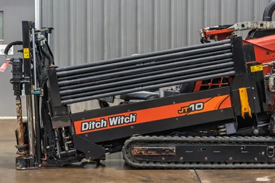 Side profile of 2018 Ditch Witch JT10 HDD showing drill pipe rack, rubber tracks, operator seat, and drill head assembly.