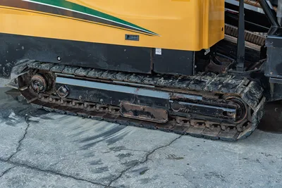 2019 Vermeer D40x55 S3 HDD drill close-up of rubber track undercarriage, worn with mud buildup, yellow chassis visible above