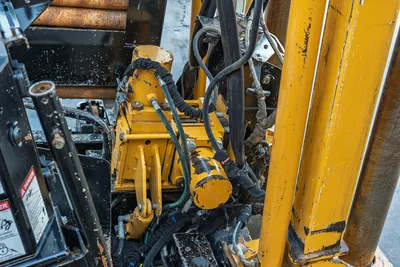 2021 Vermeer D23x30 S3 spindle/gearbox close-up showing hydraulic hoses, wear from use, yellow drive components, and drill pipe rack
