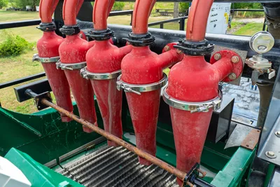 2023 American Augers M300DH desander/desilter hydrocyclone cones, red, with clamp fittings over shaker screen deck