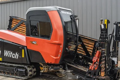 Side view of 2021 Ditch Witch AT40 All Terrain HDD, featuring enclosed cab, pipe racks, and heavy-duty steel tracks.
