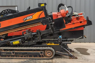 Side view of 2021 Ditch Witch JT25 HDD drill showing hydraulic pipe loader, tracks, stabilizer feet, and engine frame.
