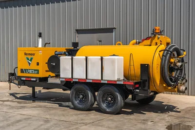 Vermeer LP873SDT trailer-mounted vacuum excavator, 3/4 view, yellow debris tank, engine enclosure, white water tanks, flex hose, tandem axle